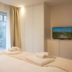 Schlafzimmer mit Bett, TV und Fenster zum Garten