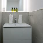 Waschbecken mit Spiegel, Handtüchern und Seifenspender.