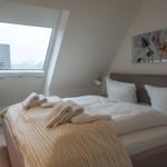 Schlafzimmer mit Dachschrägen, Bett, Fenster und Wandbild.