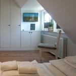 Bedroom with bed, wardrobe, and TV mounted on the wall.