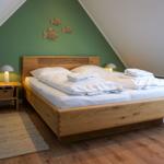 Bedroom with wooden bed, green wall, and fish decoration.