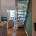 Entrance area with wooden staircase and living area with TV and window.