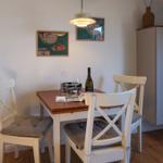 Dining table with three chairs, wall art, and cabinet in room.
