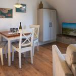 Dining area with table, chairs, and TV in a room with hardwood floor and cabinet.