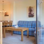 Living and dining area with blue checkered sofa and wooden table.