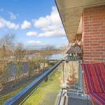 Balcony with lounge chair and view of water and trees.