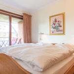 Bedroom with double bed, window, and painting on the wall.