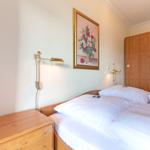 Bedroom with double bed, wooden closet, and wall painting with flowers.
