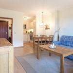Living and dining area with blue checkered sofa and wooden table.