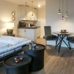 Schlafzimmer mit kleiner Küche und Essbereich mit Tisch und zwei Stühlen.