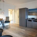 Wohnraum mit grauem Schrank, Tisch, Stühlen und Wandbild.