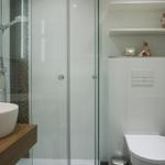 Badezimmer mit Dusche, Waschbecken und Toilette. Regal mit Figuren.
