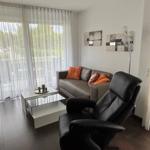 Wohnzimmer mit Sofa, Sessel und Fenster mit Jalousie.