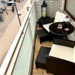 Terrasse mit Sitzgruppe und Tisch. Blick auf belebte Straße.