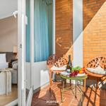 Balcony with two chairs and table, fruit and bottle. Bedroom visible through open door.