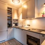 Modern kitchen with white cabinets, countertop, and built-in stove.