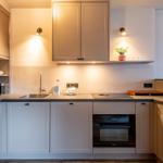 Kitchen with cabinets, sink, stove, and oven. A plant sits on a shelf.