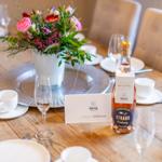 Set dining table with flower vase, glasses, and bottle.