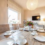 Wooden table with chairs, window and TV in dining room.