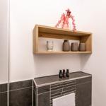 Wall shelf with vases and bottles above sink