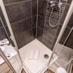 Shower cabin with dark tiles and white towels