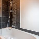Bath with bathtub and shower with dark tiles