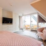 Bedroom with bed, TV, and balcony access.