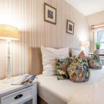 Bedroom with bed, nightstand, and window. Walls covered with striped wallpaper.
