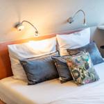 Double bed with pillows and wall lamps under sloped ceilings