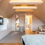 Bedroom with sloped ceiling, sofa, TV, and sleeping area.