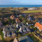 Village with houses, green areas, and sea view