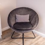 Round gray seating with pillow next to white dresser.