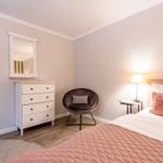 Bedroom with bed, nightstand, lamp, chair, and dresser.