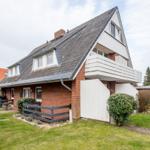 House with balcony, garden, and tiled roof. Modern design with wooden and stone cladding.