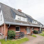 House with red brick and gray roof, lawn and paved path in front.