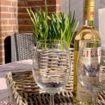 Table with wine glasses, bottle, and plant in basket on terrace.