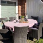Round table with chairs, tablecloth, and candles on terrace.