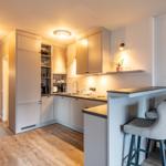 Modern kitchen with countertop and bar stools. View into dining room.