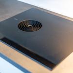Schwarze Induktionskochplatte mit Ventilationsöffnung und Markenlogo.