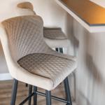 Hochlehnerstühle mit Quiltmuster stehen an der Küchenbar.