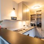 Küche mit Arbeitsplatte, Spüle, Dunstabzug und Schränken.