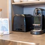 Kaffeemaschine, Toaster und Wasserglas auf Küchenarbeitsfläche
