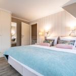Schlafzimmer mit Bett, Kleiderschrank und Wandbeleuchtung.
