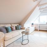 Wohnbereich mit Sofa, Tisch und Fenster unter Dachschräge