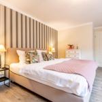 Schlafzimmer mit Bett, Nachttisch und Schrank an der Wand mit Streifen.