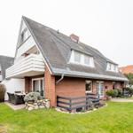 Ferienhaus mit Balkon, Garten und Terrasse. Modernes Design mit Steinmauern und Pflanzen.