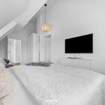 Bedroom with sloped ceiling, bed, TV, and pendant lamp.