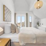 Bedroom with bed, windows, and ceiling lamp.