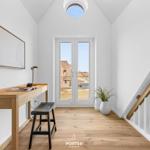 Helle Eingangshalle mit Schreibtisch, Pflanze und Treppe. Durch Fenster Blick auf Dachstuhl.