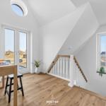 Helle Wohnung mit Holzboden, Schreibtisch, Treppe und Fenstern.